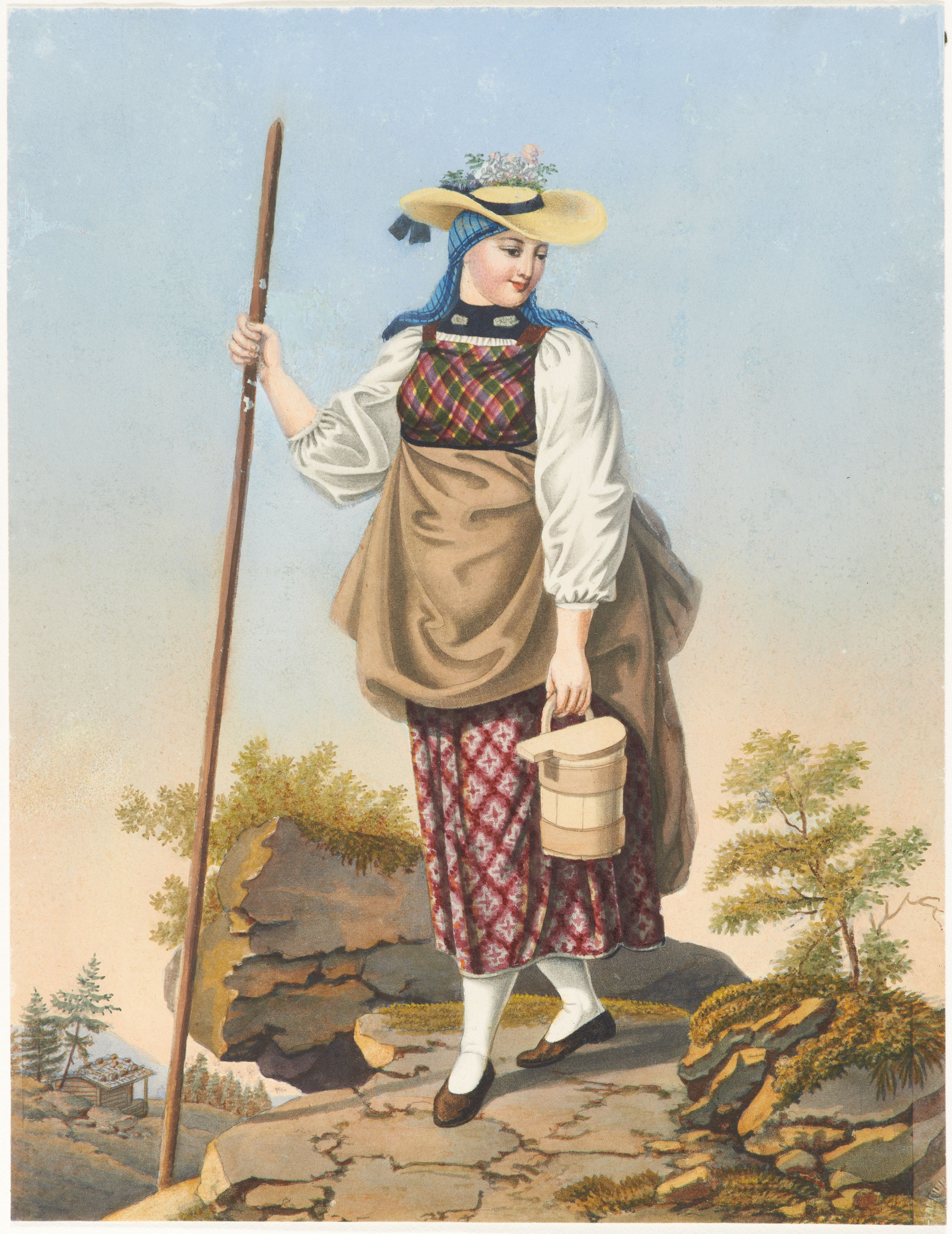 Ragazza con vestito tradizionale dell’Oberhasli con velo, cappello di paglia, bastone da montagna e secchio del latte, in cammino su un suolo roccioso